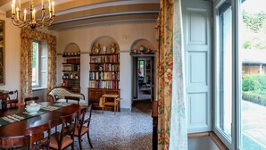 Un comedor con un cuadro grande, una araña y una estantería llena de libros.