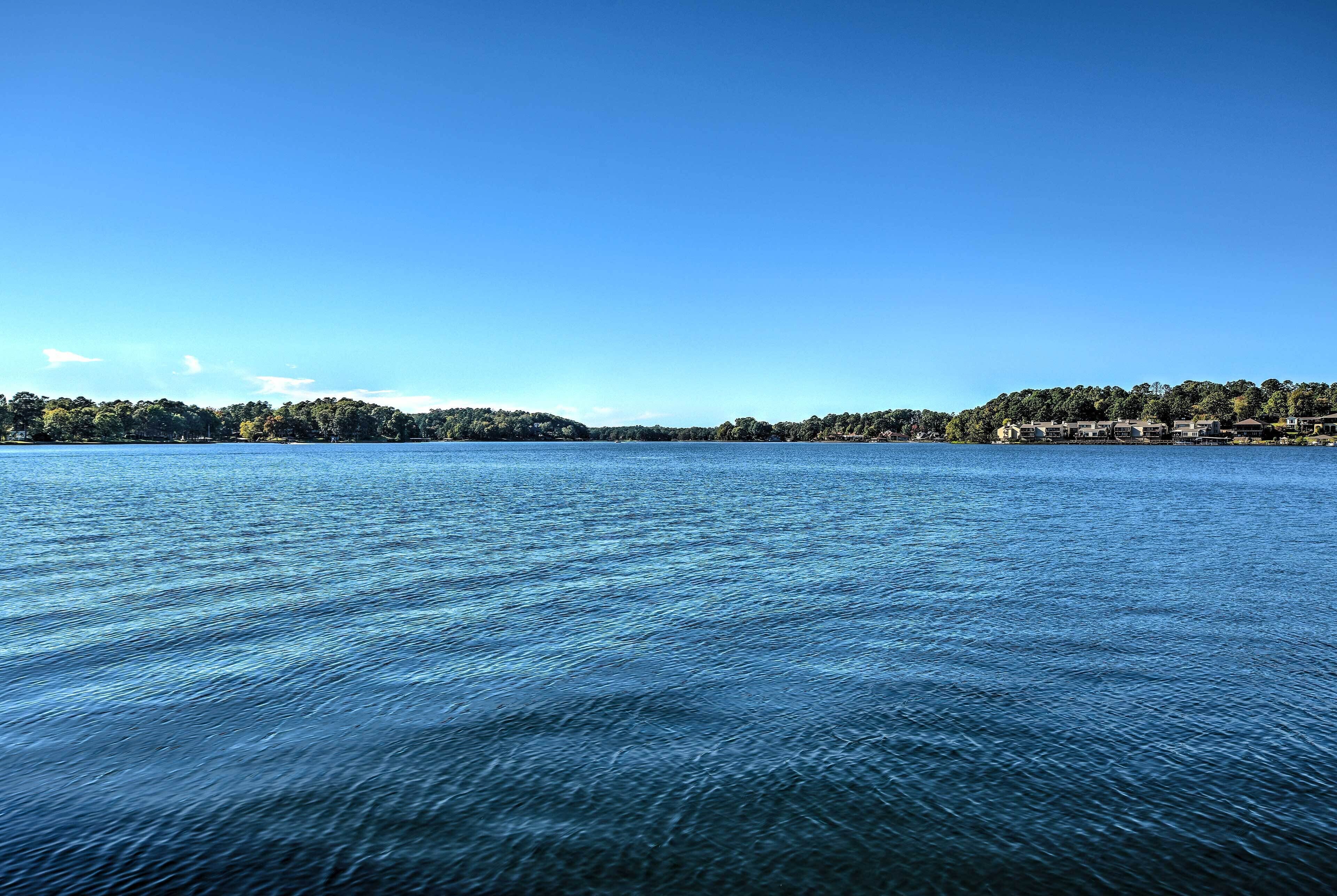 Un llac tranquil amb un cel clar i una riba llunyana amb edificis.