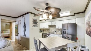Una cocina moderna con comedor, que incluye una mesa y sillas de madera, un ventilador de techo y un refrigerador.