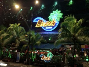 Un establecimiento con temática playera, con letreros de neón, palmeras y una zona de bar.