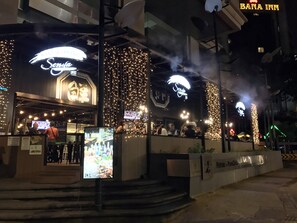Un restaurante con terraza, señalización iluminada y entrada visible.