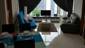 A modern living room with a blue sofa, a grey sofa, a coffee table, and a TV on a stand.