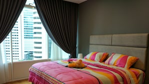 A hotel room with a large bed, a view of tall buildings, and a window with curtains.