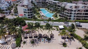 Un complexe hôtelier doté d’une piscine, d’une plage avec des chaises longues et de plusieurs bâtiments.