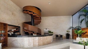 Un moderno vestíbulo con una escalera espiral, mostrador de recepción, zona de estar y plantas en macetas.