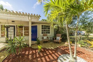 A house with a porch, a blue door, and a garden with plants and a small table.