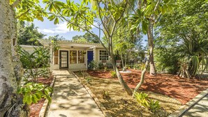 A house with a front porch, a small garden with red mulch, and a pathway leading to the entrance.