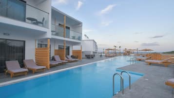 Una piscina al aire libre, sombrillas, sillones reclinables de piscina