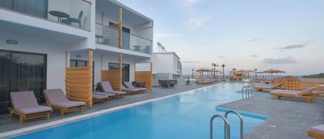 Una piscina al aire libre, sombrillas, sillones reclinables de piscina