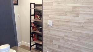 A kitchen with a wooden countertop, a white bowl, a potted plant, and a black shelf unit with books and snacks. - Chic Denver Tech studio (Centennial)