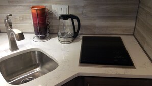 A kitchen with a stainless steel sink, a kettle, and a black induction cooktop. - Chic Denver Tech studio (Centennial)