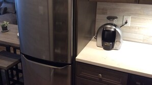 A kitchen with a stainless steel refrigerator, a coffee maker, and a small potted plant on the counter. - Chic Denver Tech studio (Centennial)