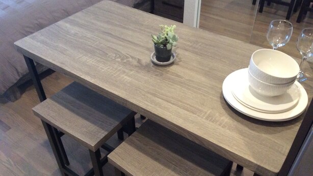 A wooden dining table with a small potted plant, a bowl, and wine glasses. - Chic Denver Tech studio (Centennial)