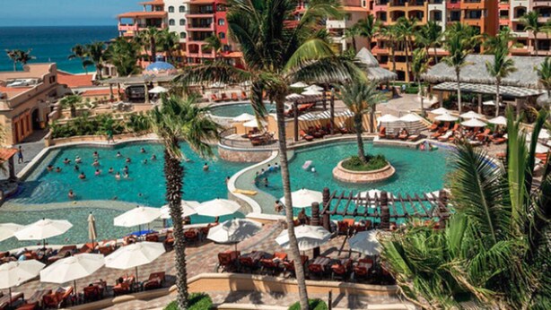 A resort with a large central pool, multiple smaller pools, and a variety of sun loungers and umbrellas. - Downtown Cabo San Lucas Suite with Ocean and Harbor Views (Cabo)