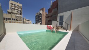 Une piscine sur le toit, avec une eau cristalline, entourée d’immeubles.