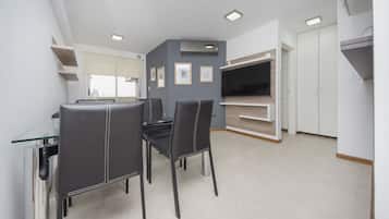 A modern kitchen with a dining area, featuring a glass table, black chairs, and built-in shelving.