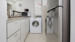 Une cuisine compacte équipée d’un lave-linge, d’un four à micro-ondes et d’un petit réfrigérateur.