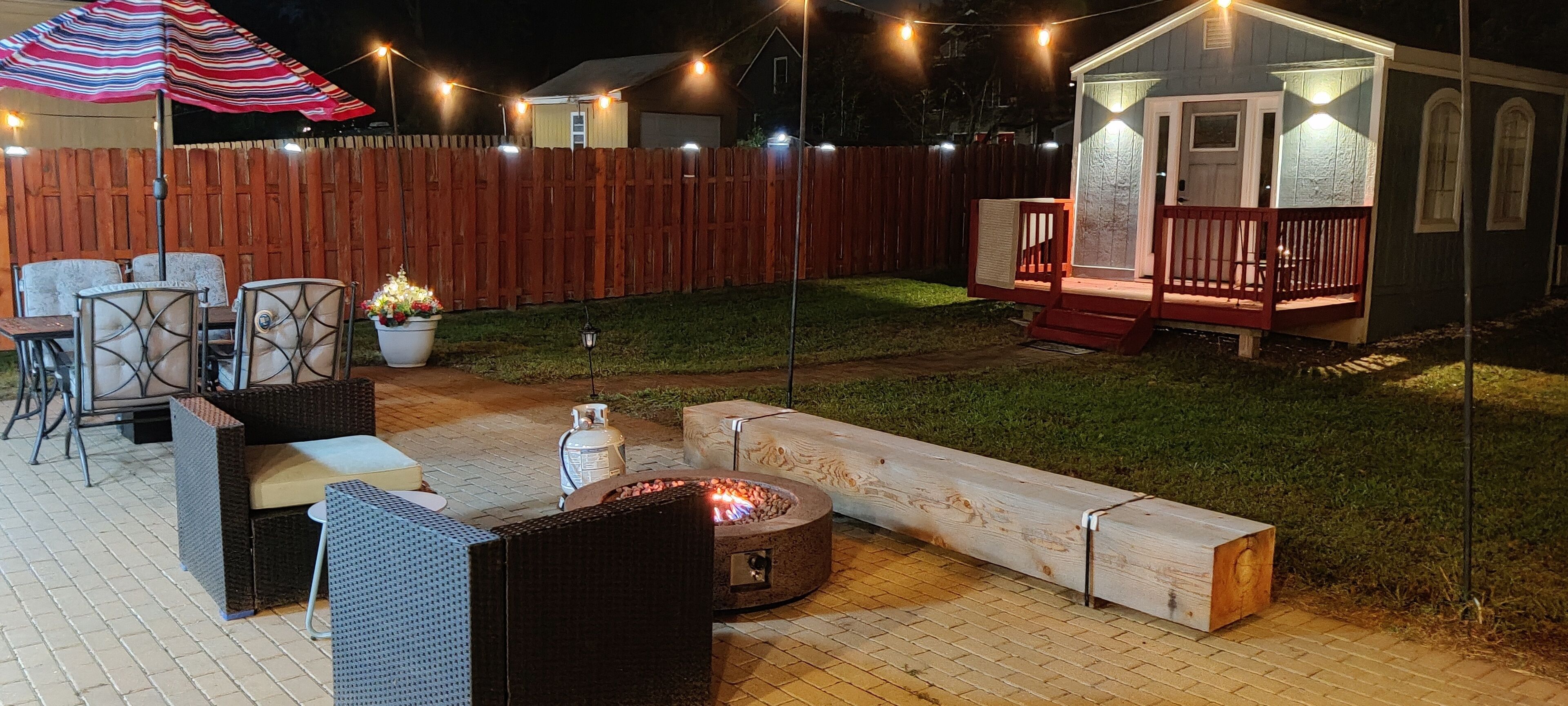 Un patio trasero con un hogar para fuego, mobiliario exterior y una pequeña terraza.