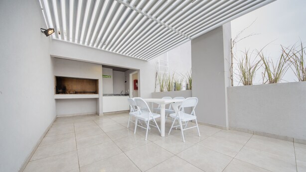 A modern outdoor patio with a white table and chairs, a tiled floor, and a white ceiling structure. - WX4 Venezuela Apartment (Córdoba)