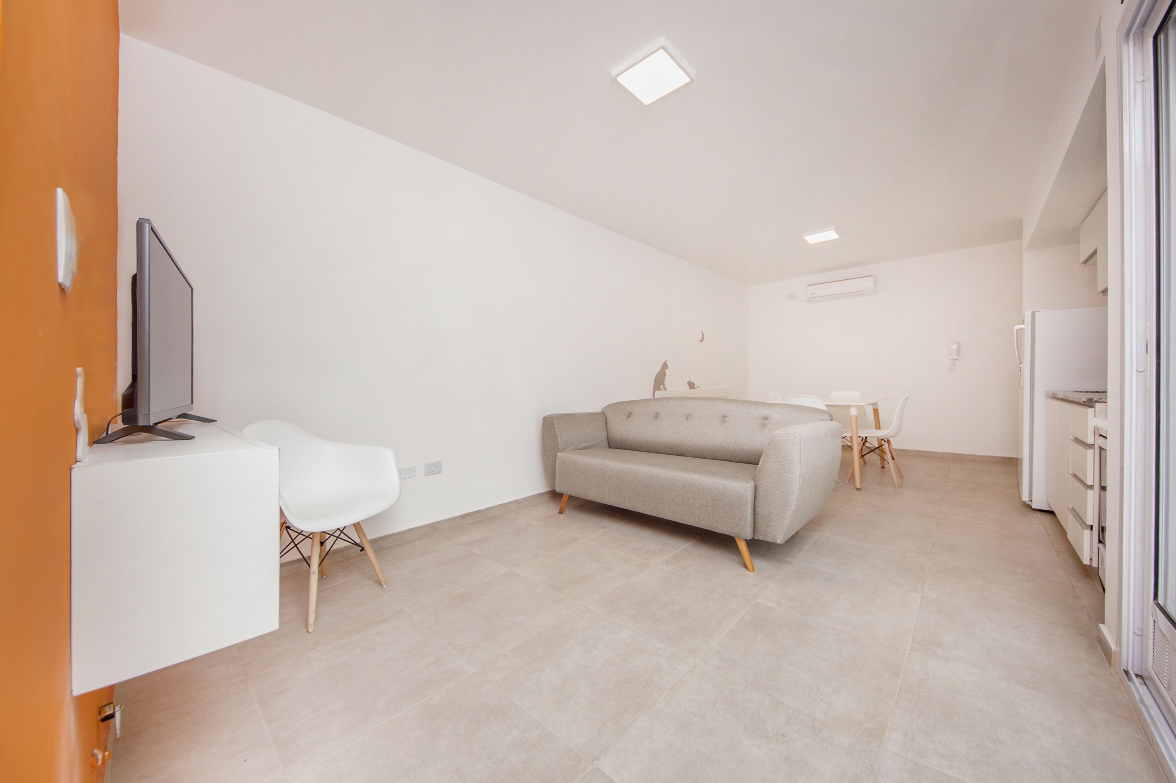 Un salon moderne et minimaliste, avec un canapé, une petite table et un téléviseur.