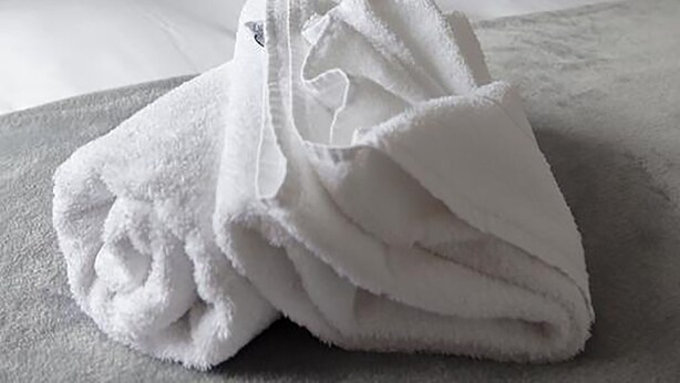 A neatly made bed with white linens and a folded white towel on the bed. - The Robin Coach House (Hereford)
