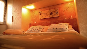 A neatly made bed with patterned pillows and a headboard with wall-mounted lights.