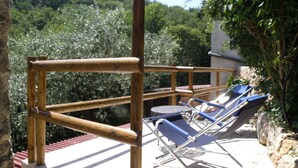A wooden deck with a railing, a small table, and two blue lounge chairs.