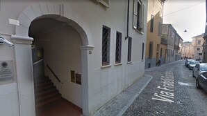 A street with a cobblestone road, a building entrance with an archway, and a Via Franca sign.