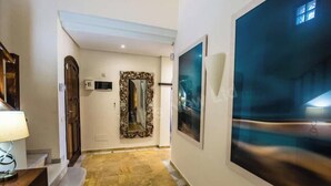 Un corridoio con una porta in legno, uno specchio, una lampada a parete e un'ampia finestra con vista.