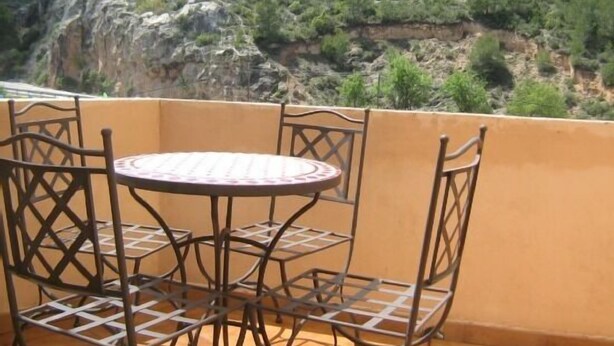 Una terraza con una mesa redonda y cuatro sillas, con vistas a un paisaje montañoso.