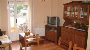 Una sala de estar acogedora con un aparador de madera, un televisor y una mesa de comedor con sillas.
