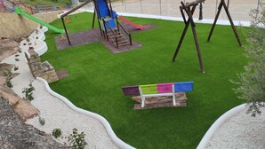 Un parque infantil con tobogán, columpios y una estructura para escalar.
