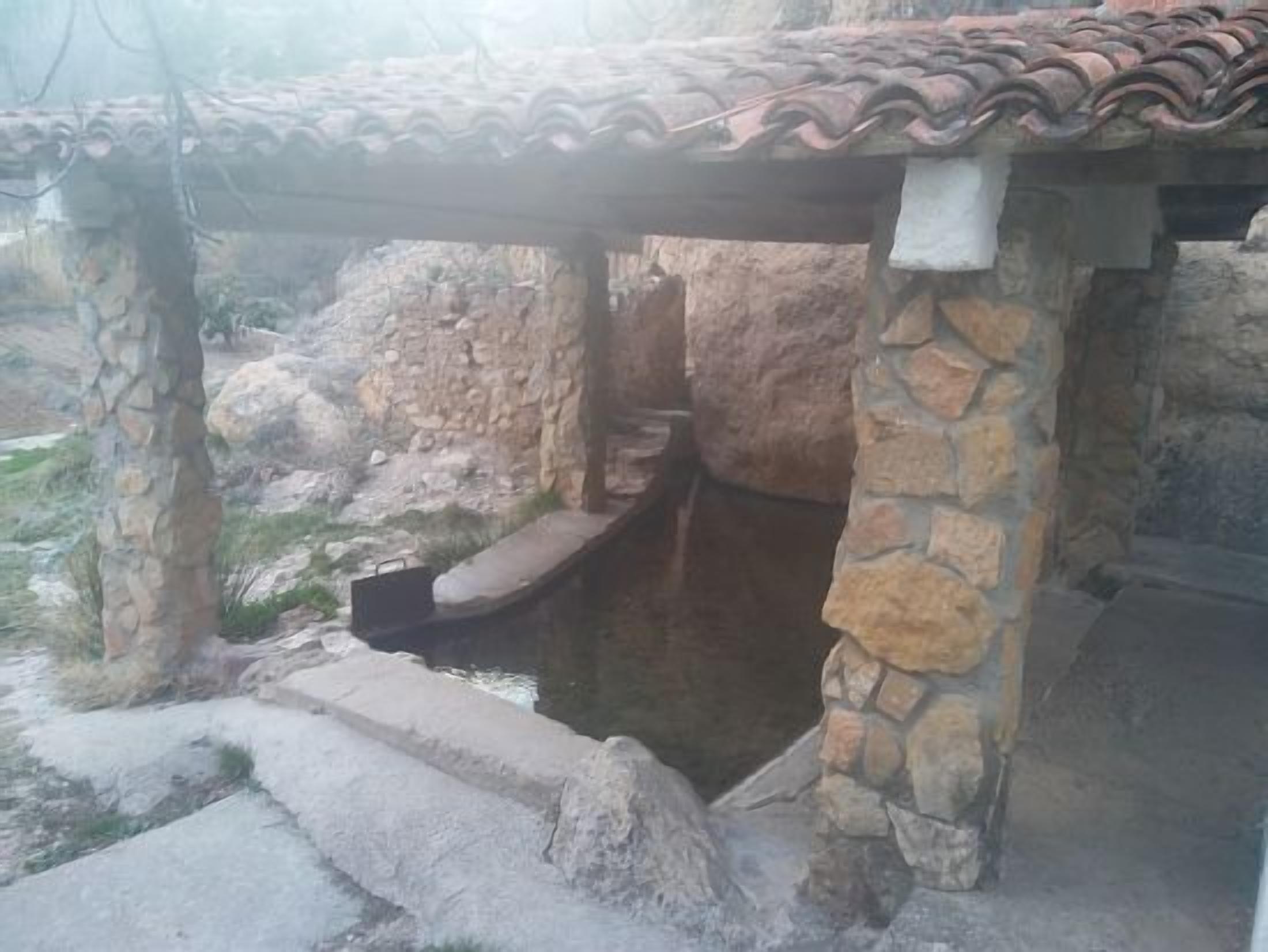 A stone structure with a tiled roof, possibly a historical building or monument.