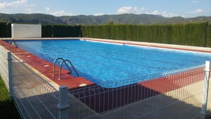 Una piscina con cubierta roja, barandillas metálicas y vistas a montañas al fondo.
