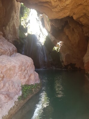 Una cueva con cascada y un estanque.