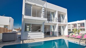 Un bâtiment moderne à deux étages, doté d’une piscine et d’un espace extérieur aménagé pour se détendre.