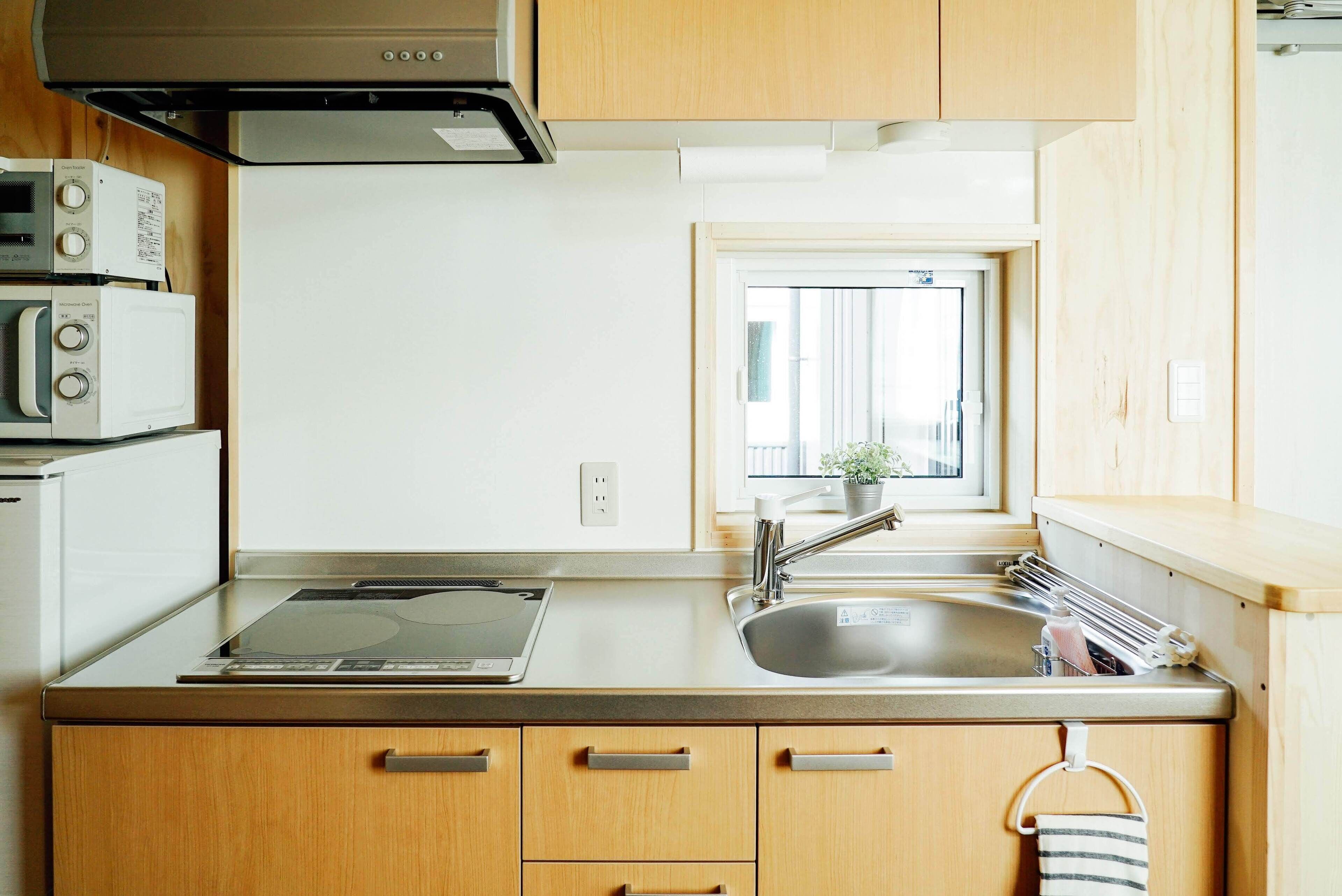 A kitchen with wooden cabinets, a stainless steel sink, and a window with a view of the outside.