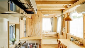 A compact kitchen with a sink, a wooden dining table, and a window with curtains. - Jstyle STAY Furano (Furano)
