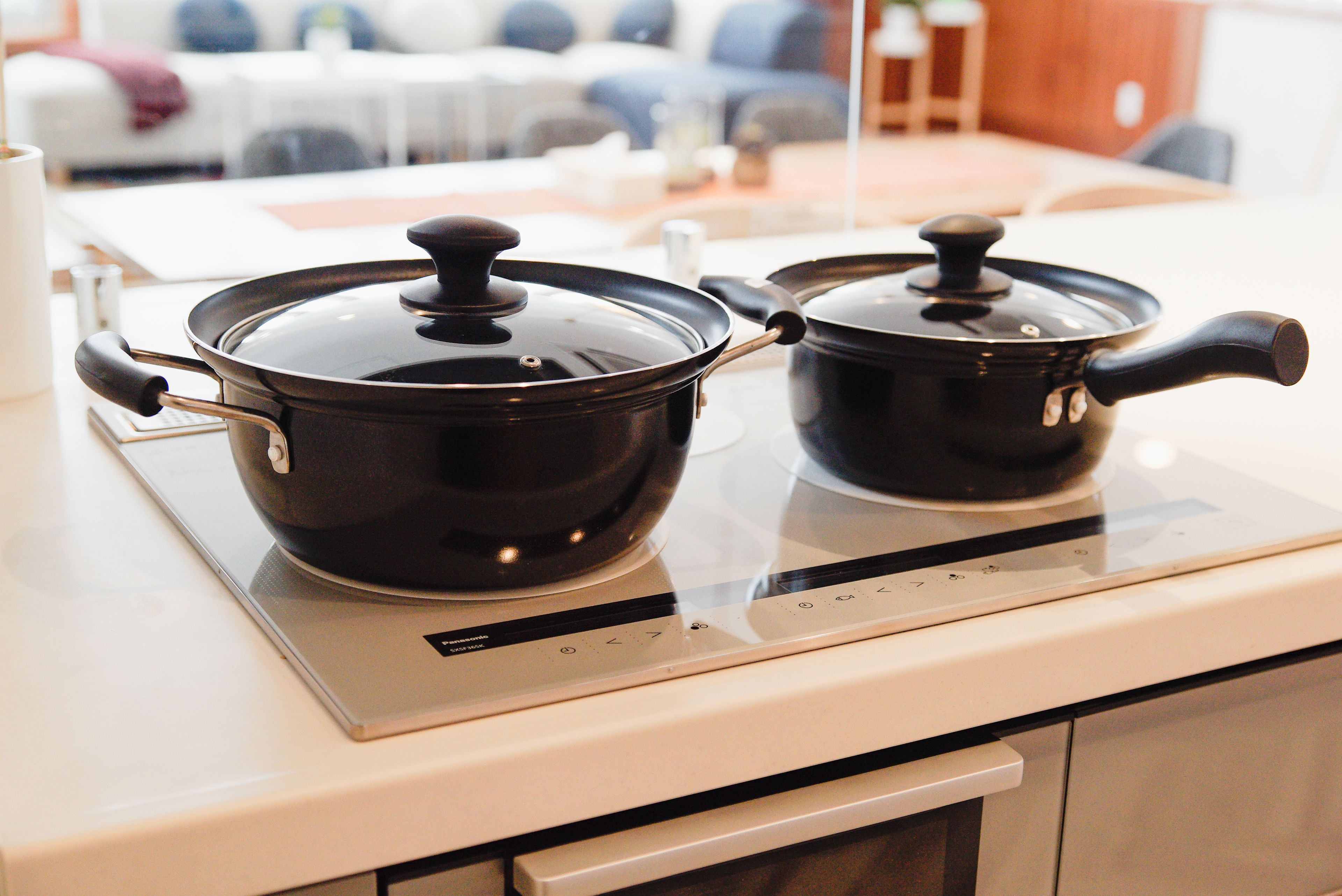 Two black pots on a modern induction cooktop.