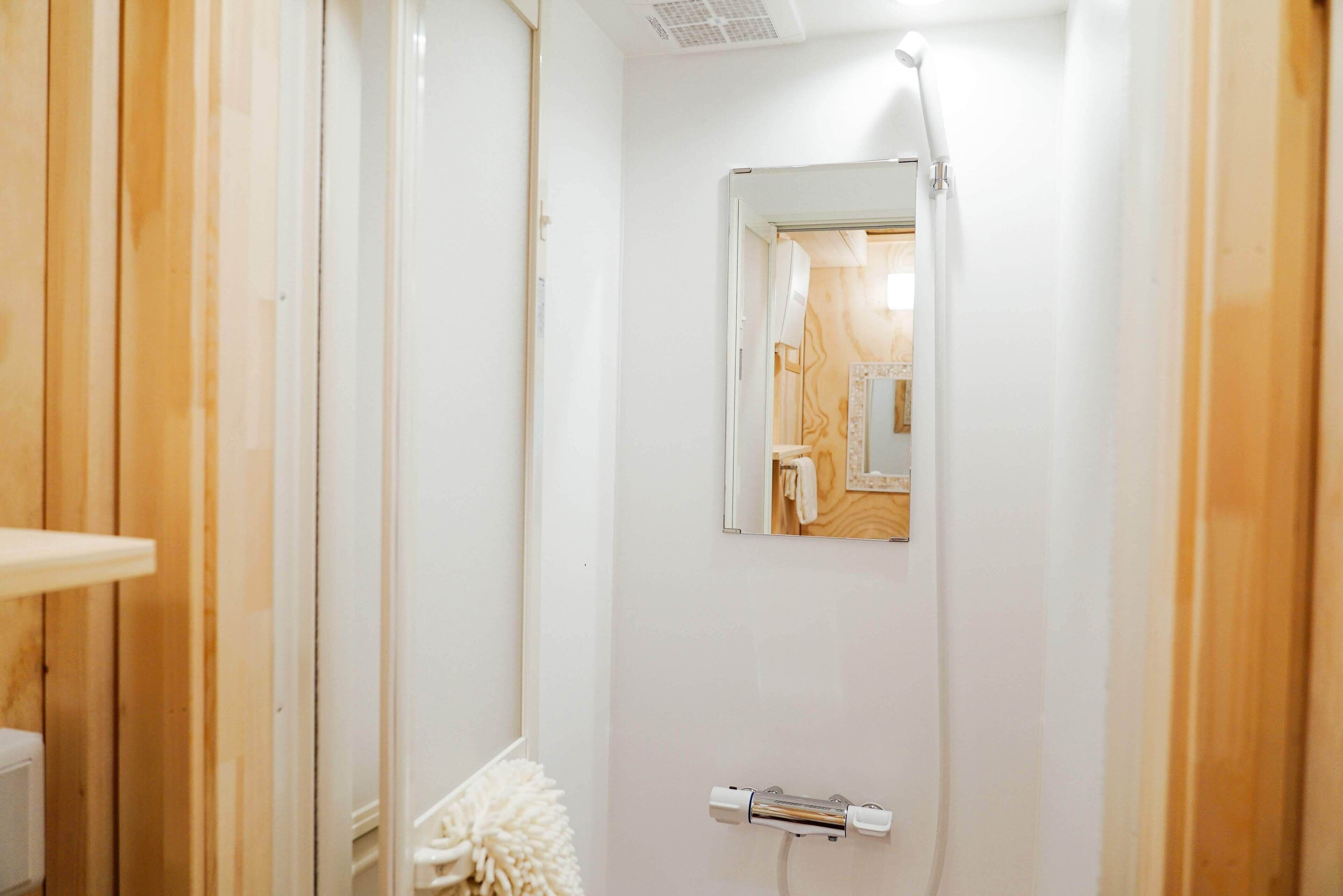 A small, white bathroom with a wooden panel wall, a mirror, and a towel rack.