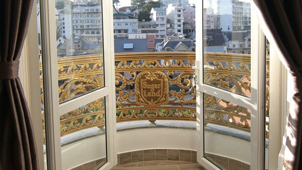 A balcony with a view of the cityscape, featuring a decorative railing and a clear sky. - Sugar Land Villa Hotel Dalat (Xuan Huong - Da Lat)