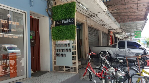 A storefront with a green wall and a sign reading "Baan Pinklao". There are multiple phone numbers and a self-check-in kiosk. - Baan Pinklao (Bangkok)