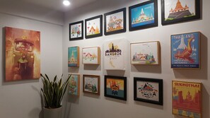 A wall with various framed travel posters and a potted plant. - Baan Pinklao (Bangkok)