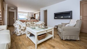 A living room with a sofa, a chair, a coffee table, and a kitchen area in the background. - Esprit du Sud Esterel (Sainte-Maxime)