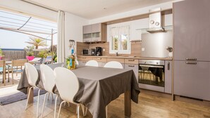 A modern kitchen with a dining area, wooden flooring, and a view of the outdoors. - Esprit du Sud Esterel (Sainte-Maxime)