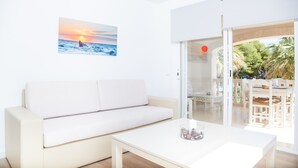 A modern living room with a white sofa, a coffee table, and a painting of a sunset over the ocean. - SUN OF THE BAY VIDALBA 3 (B2 - A3) - Apartment with sea views in Port d'Alcudia. Free WiFi (Alcúdia)