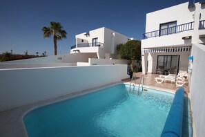A modern pool area with clear blue water, white buildings, and a palm tree in the background. - Luxury quiet southfacing Villa in Marina Rubicon with Free Wifi & heated pool (Playa Blanca)