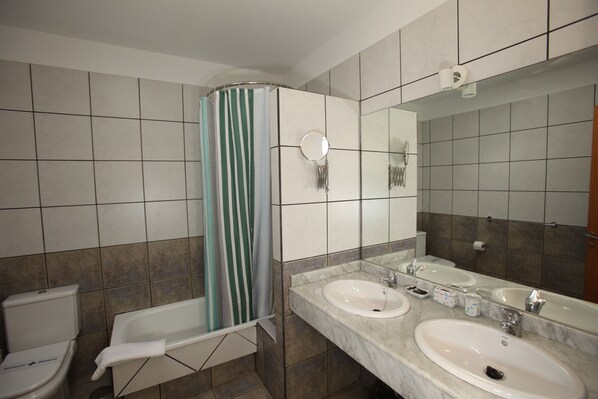 A bathroom with two sinks, a toilet, a shower with a striped curtain, and a large mirror. - Luxury quiet southfacing Villa in Marina Rubicon with Free Wifi & heated pool (Playa Blanca)