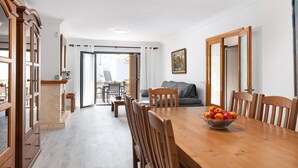 Un comedor con una mesa y sillas de madera, un cuenco de fruta y vistas al patio exterior.