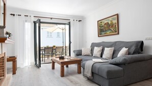 Un salón con un sofá gris, una mesa de centro de madera y un cuadro en la pared.